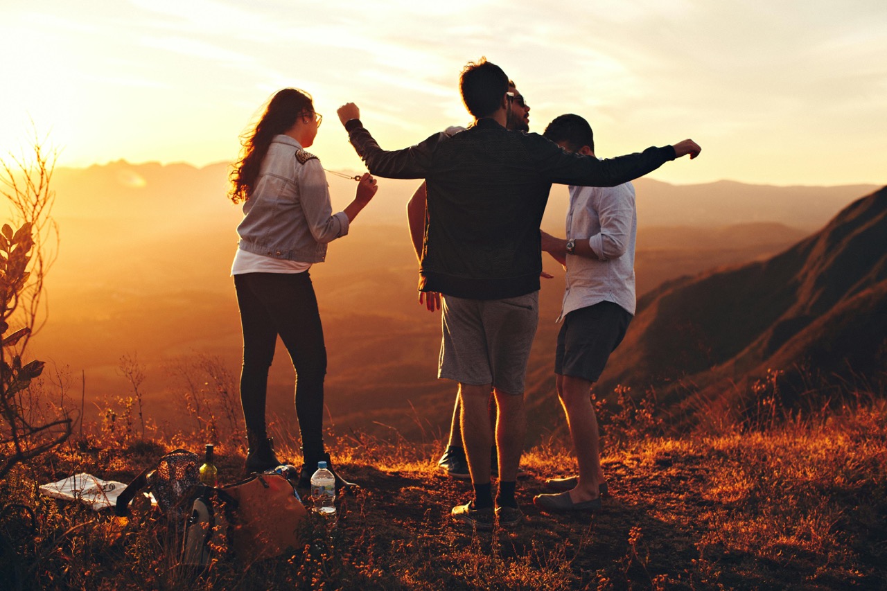 Happy people on hillside with sunset